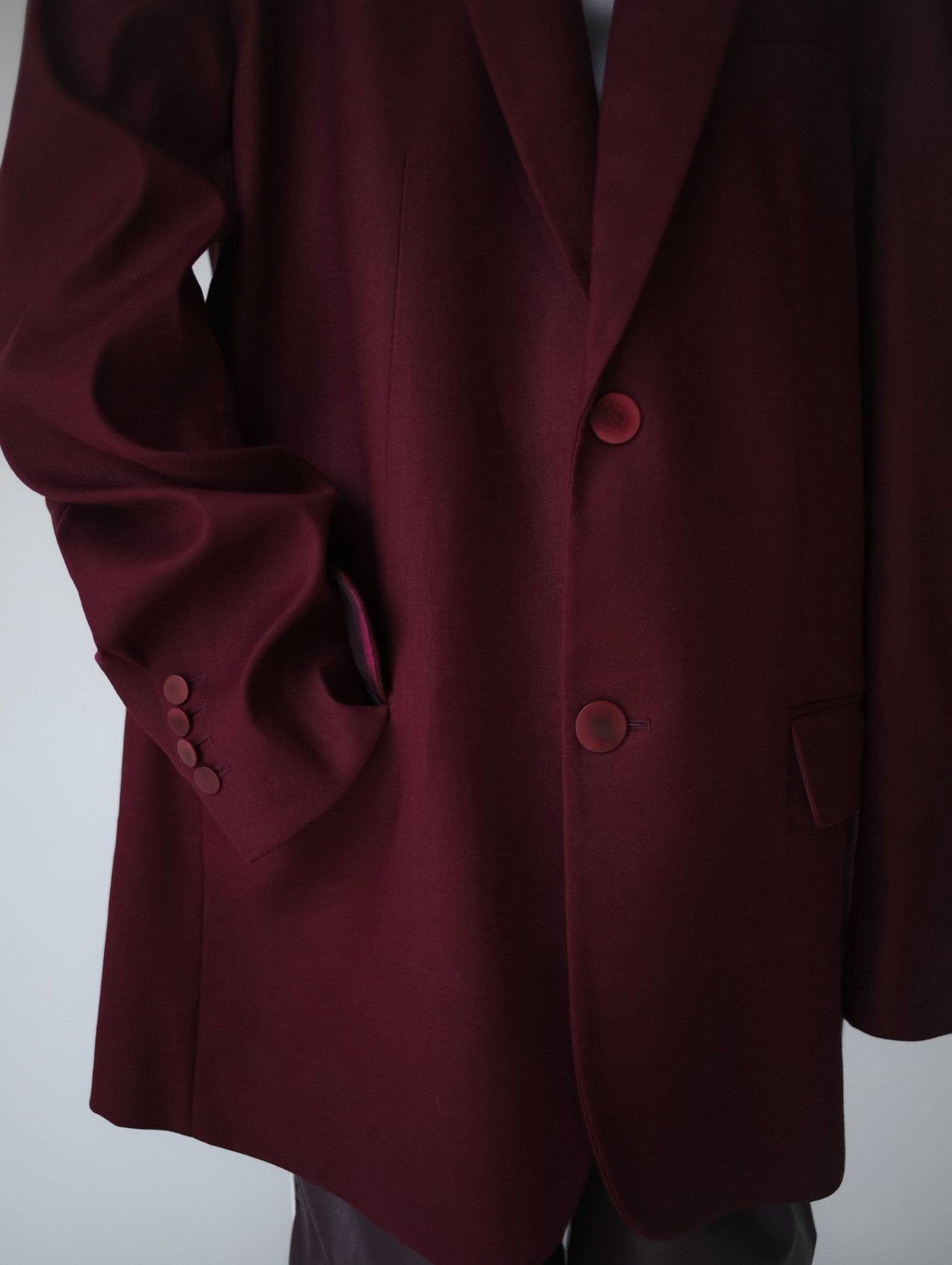 Front view of burgundy wool blazer highlighting tonal buttons and clean silhouette.