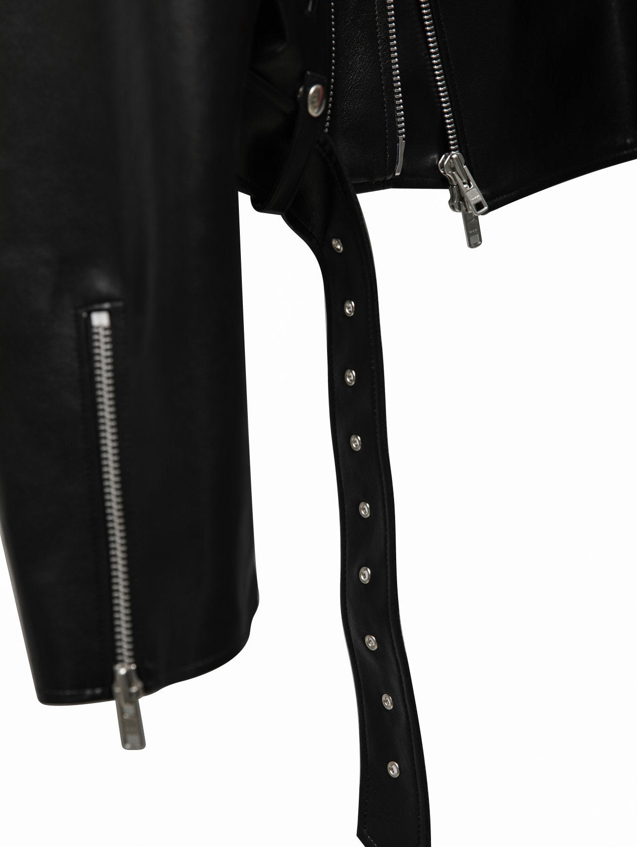 Close-up of black leather moto jacket sleeve zipper, hemline hardware, and hanging grommeted belt