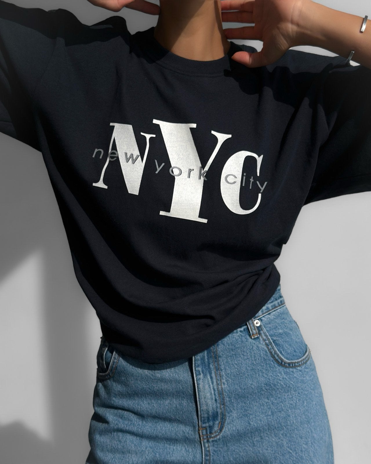 Minimalist close-up of NYC New York City lettering on oversized navy cotton t-shirt.