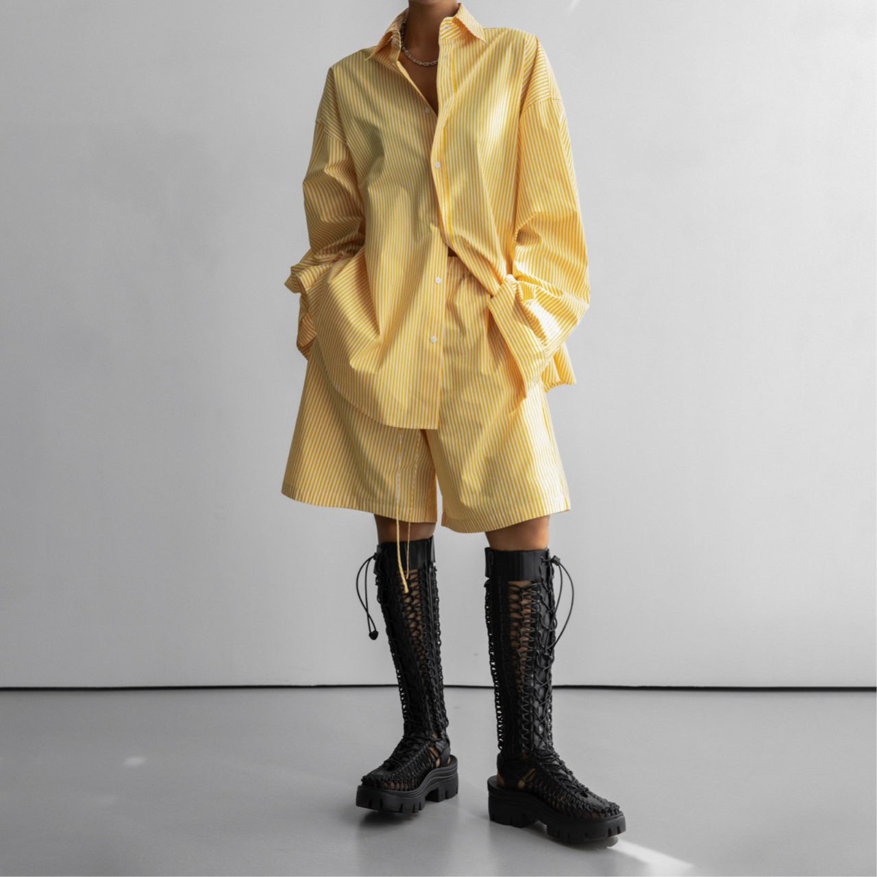 Full-body view of model in yellow striped co-ord set, featuring wide-leg shorts and oversized shirt.