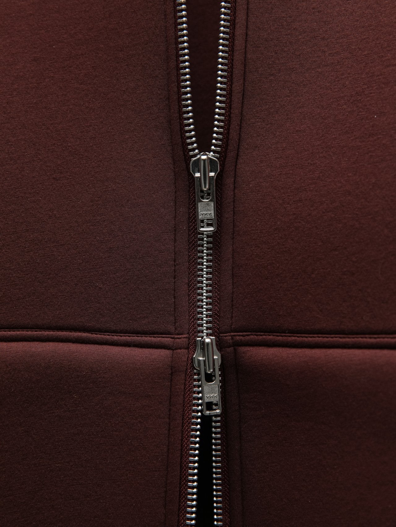 Detailed macro of two-way YKK zipper on structured hoodie