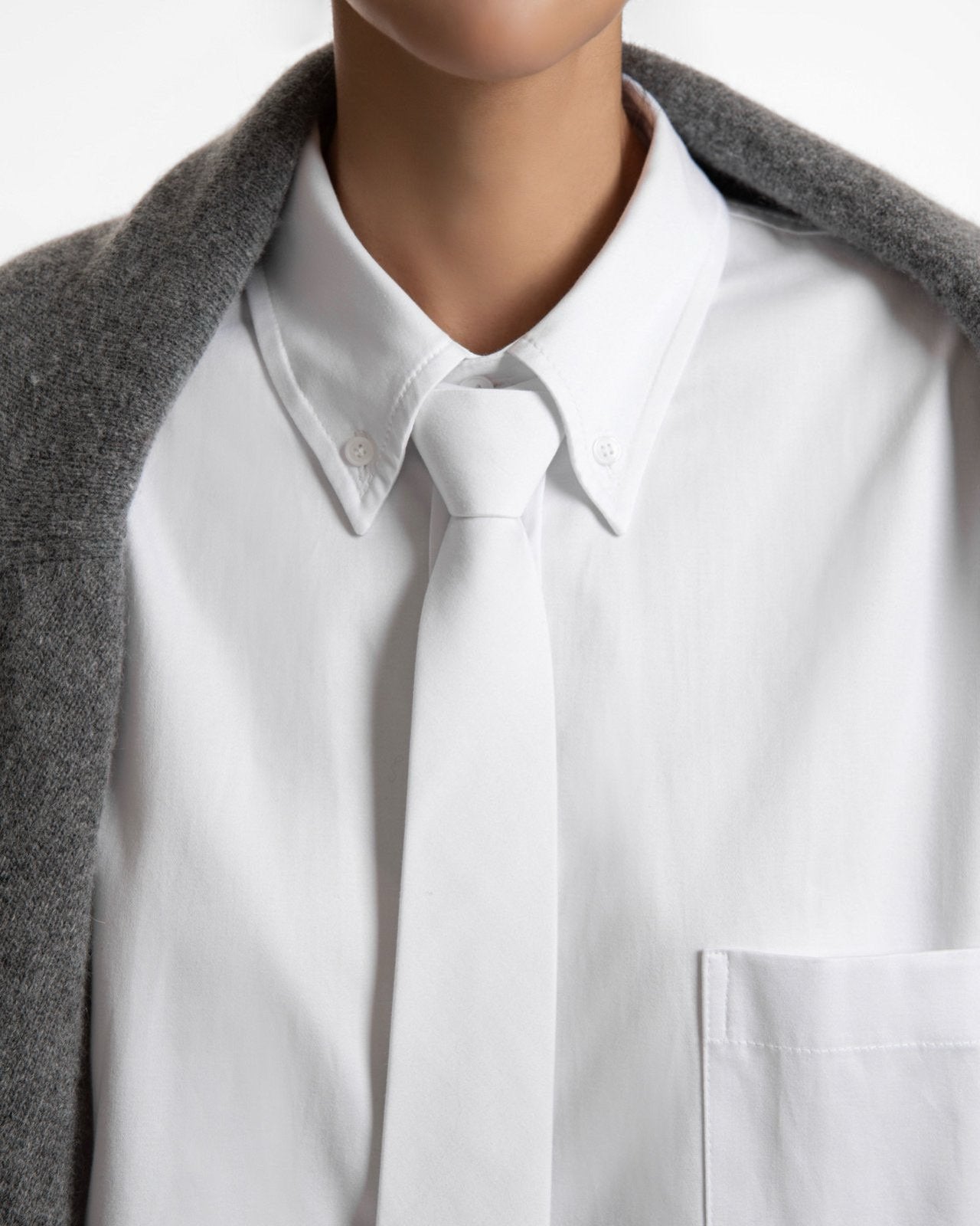 Close-up of white shirt collar with minimal tie detail — refined tailoring and crisp cotton texture.