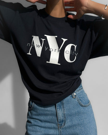 Minimalist close-up of NYC New York City lettering on oversized  navy cotton t-shirt.