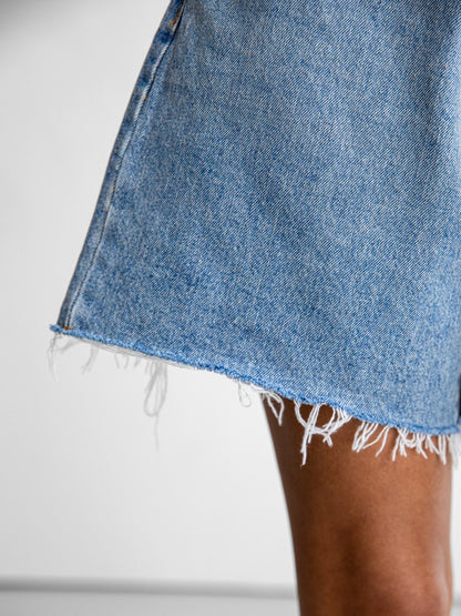 Raw hem detail of the denim shorts showing frayed edge