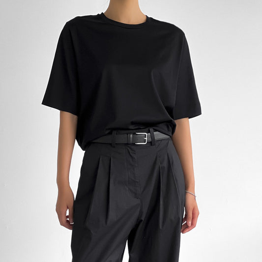 Full front view of model in black oversized t-shirt styled with high-waisted pleated trousers