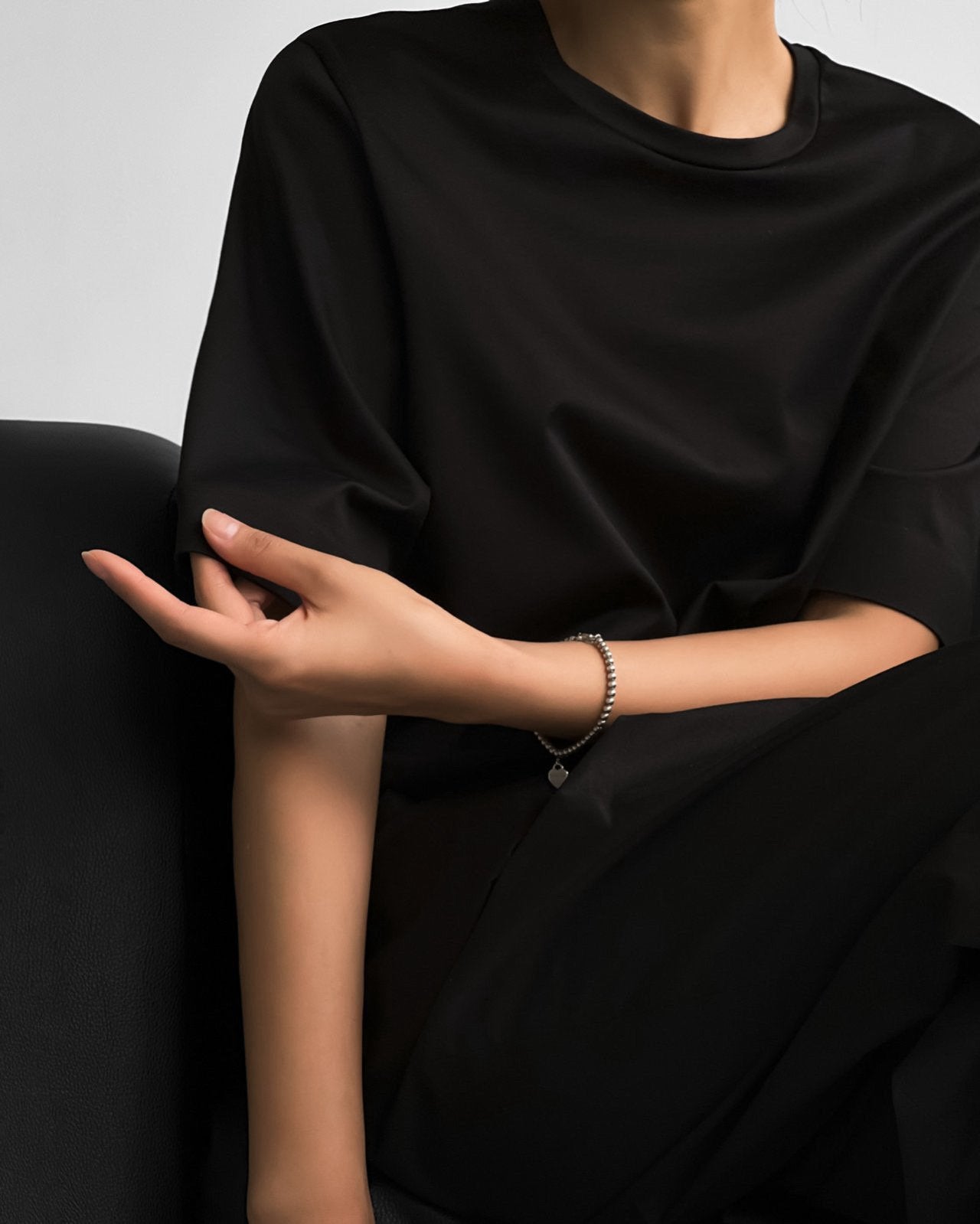 Relaxed side view of the black oversized t-shirt, showcasing sleeve detail and bracelet accessory