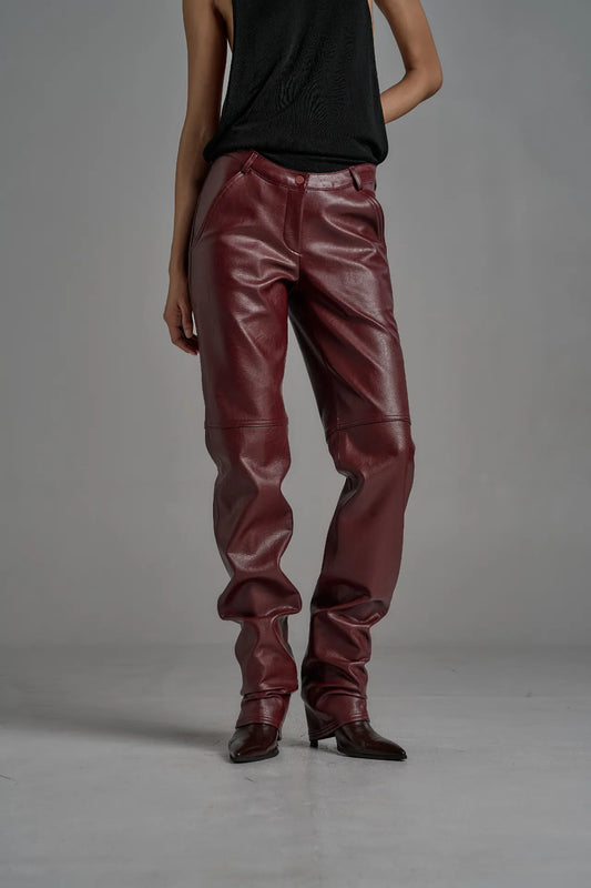 Front angle of model wearing wine leather trousers with stacked leg detail.