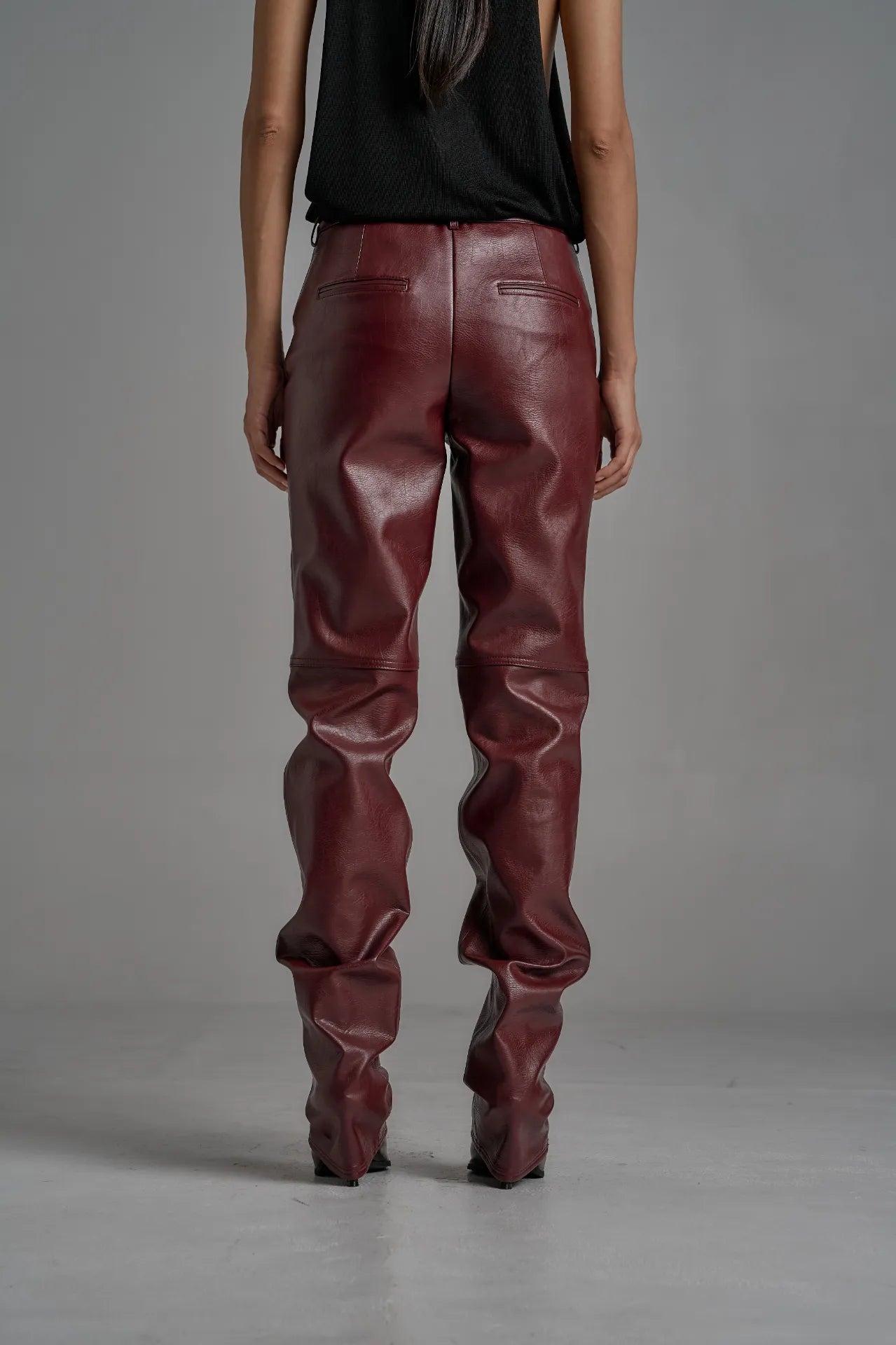 Back angle showing sculpted fit and textured sheen of wine trousers.