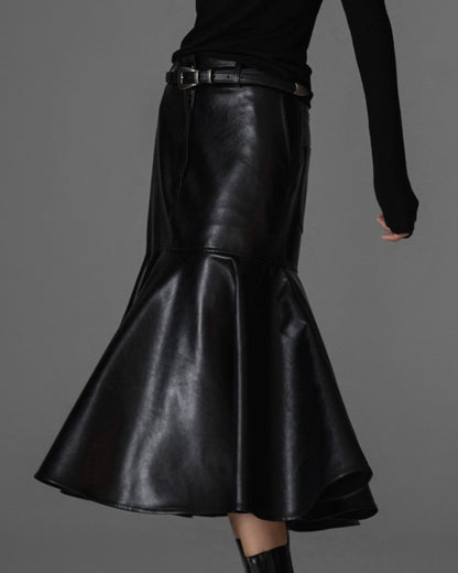 Model wearing black vegan leather mermaid-cut midi skirt with dramatic peplum flare.