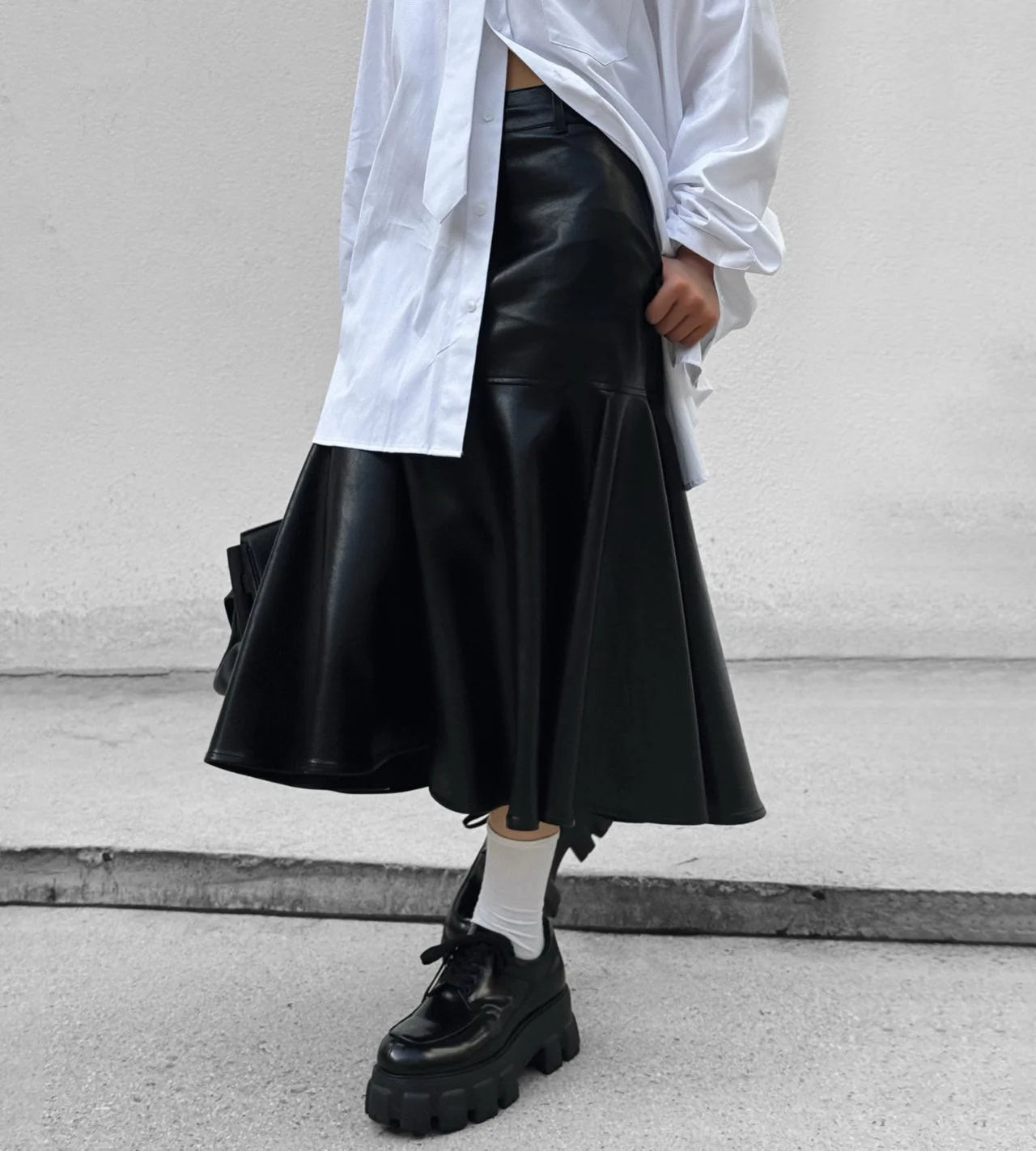 Black vegan leather mermaid skirt styled with oversized white shirt and chunky loafers.