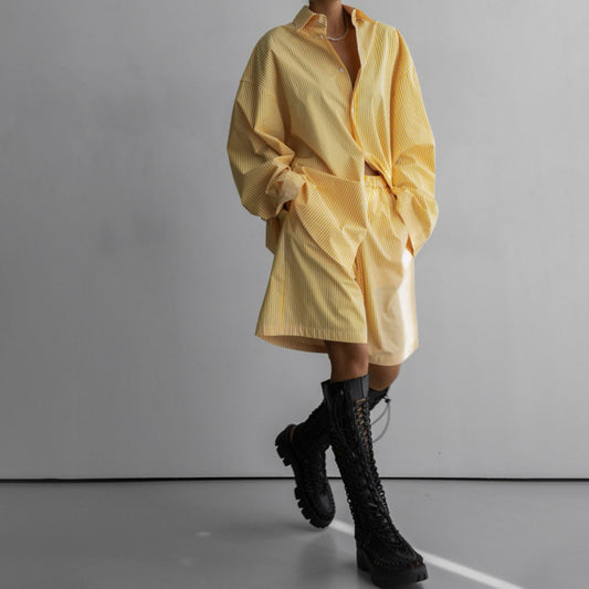 Model wearing matching yellow striped shorts and shirt, styled with tall black boots.
