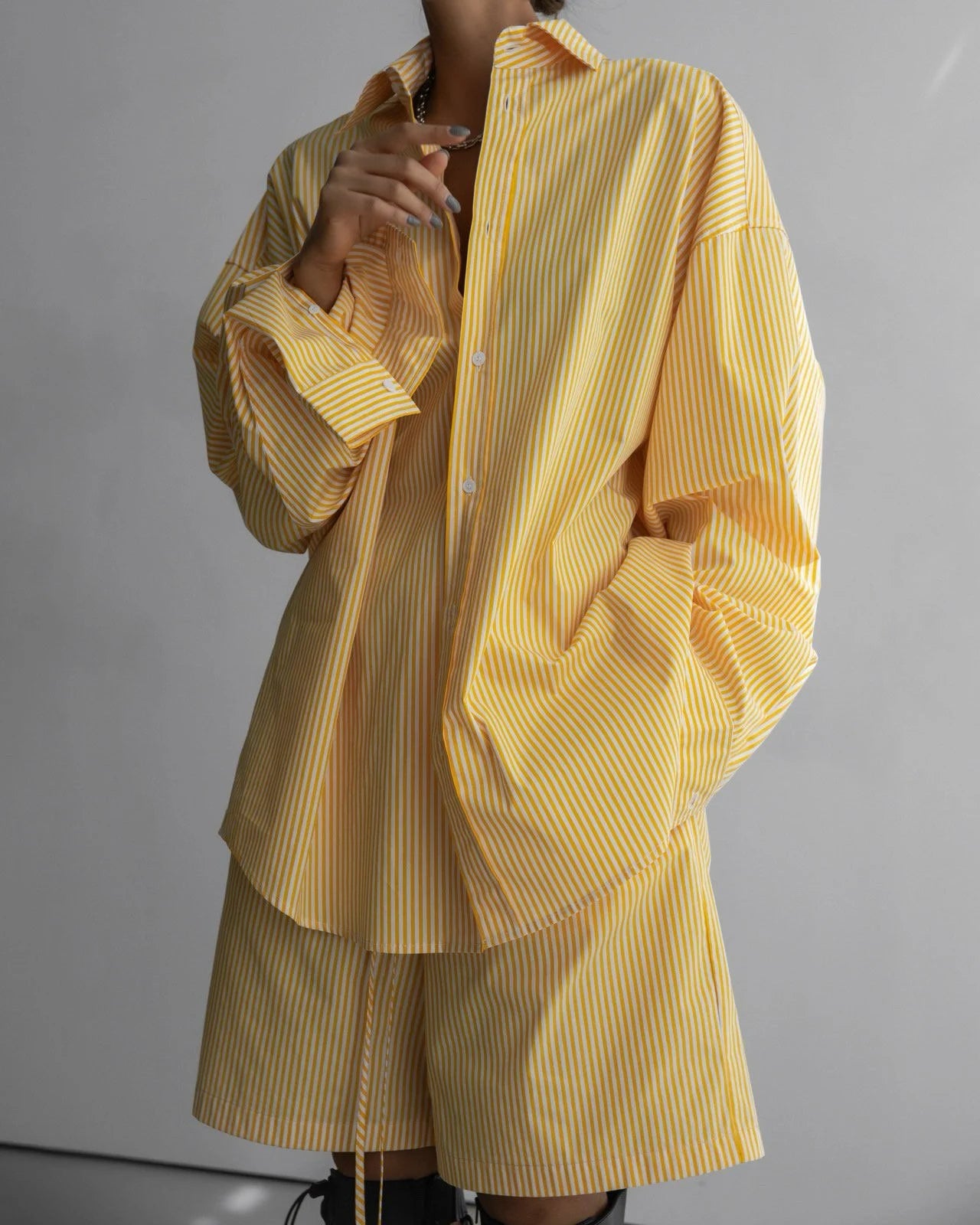 Front view of an oversized yellow striped shirt paired with matching drawstring shorts.