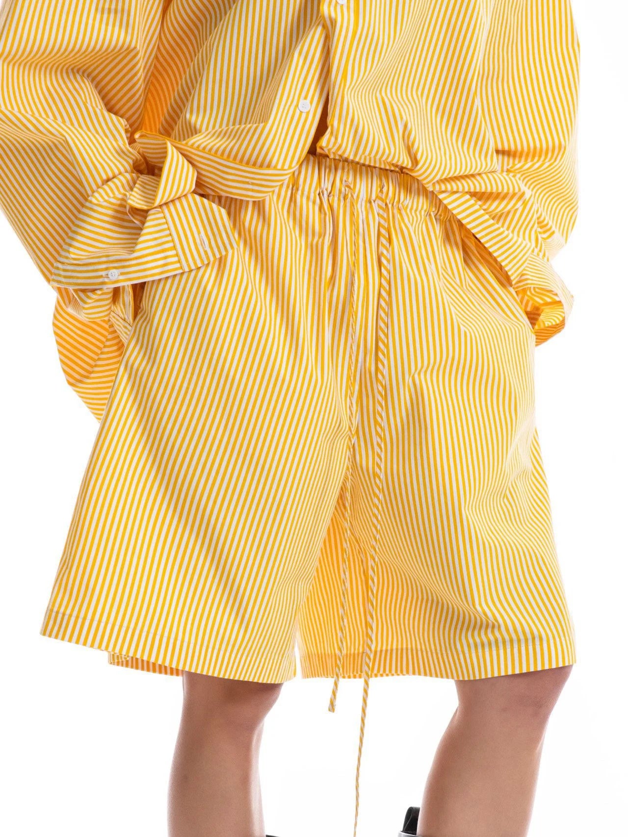 Close-up of yellow and white striped cotton shorts with drawstring waist, styled with a matching oversized shirt.