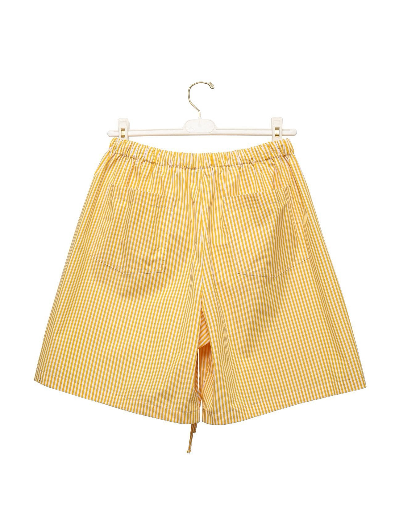 Back view of yellow striped cotton shorts hanging on a white hanger.