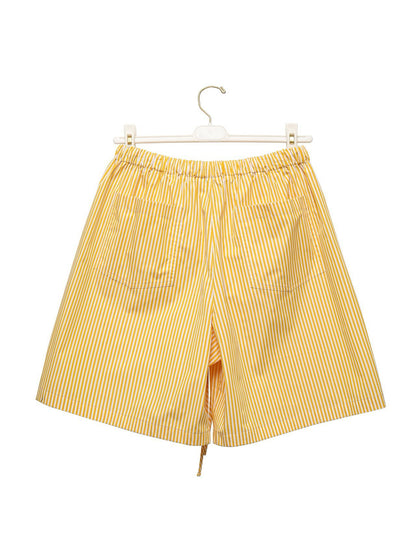 Back view of yellow striped cotton shorts hanging on a white hanger.