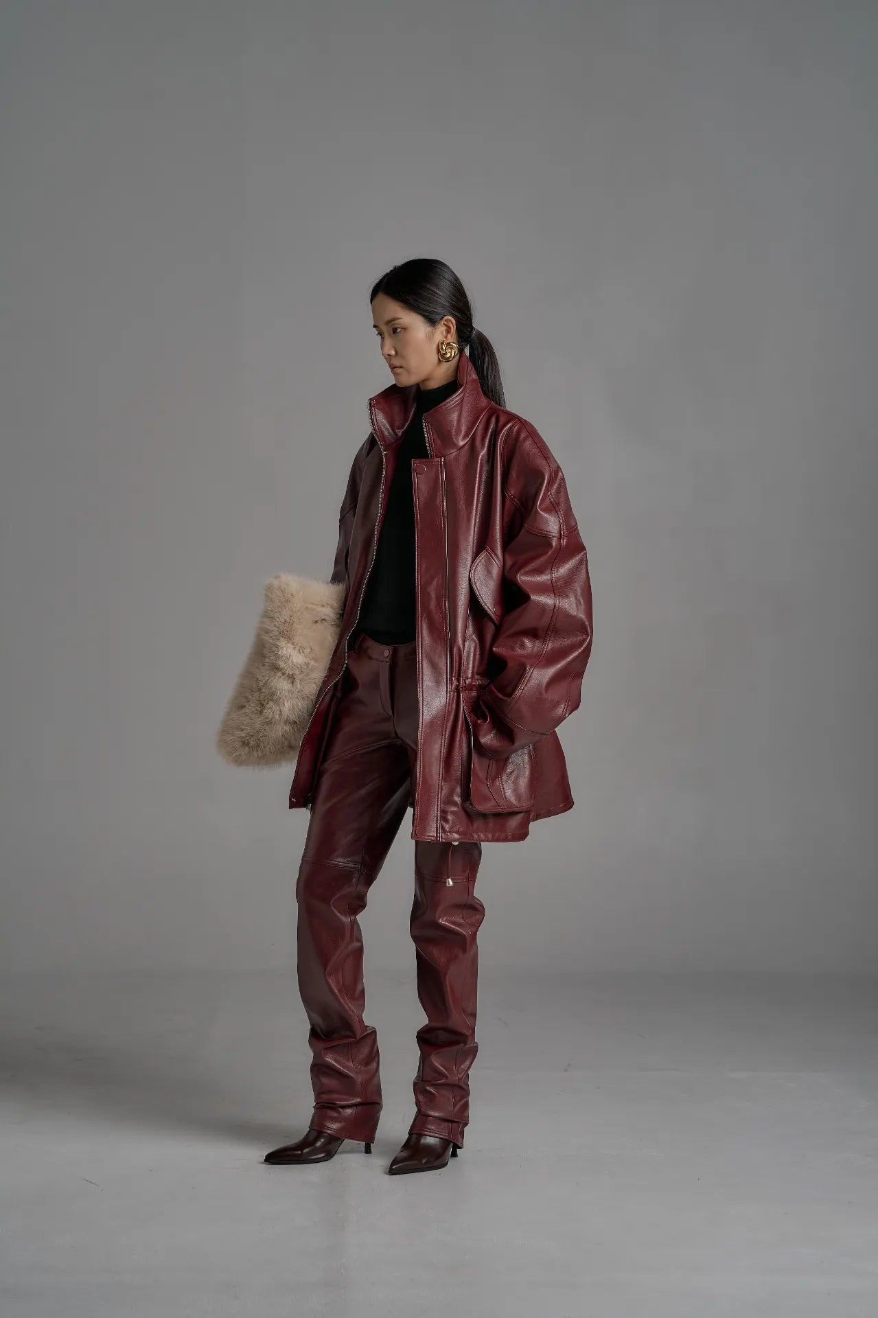 Full-body image of oversized wine leather jacket paired with matching wine pants and boots.