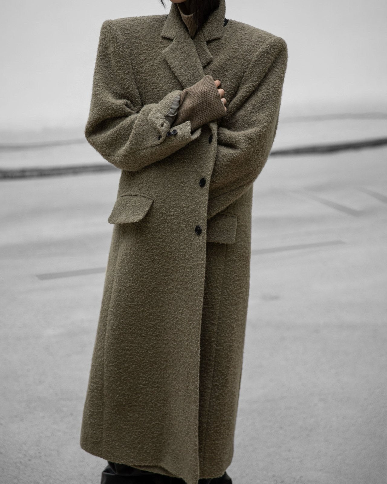 Close-up of textured alpaca wool bouclé maxi coat with lapels and buttons.