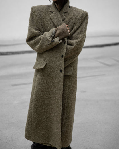 Close-up of textured alpaca wool bouclé maxi coat with lapels and buttons.