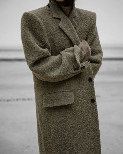 Side view of khaki beige bouclé oversized wool coat with structured shoulders.