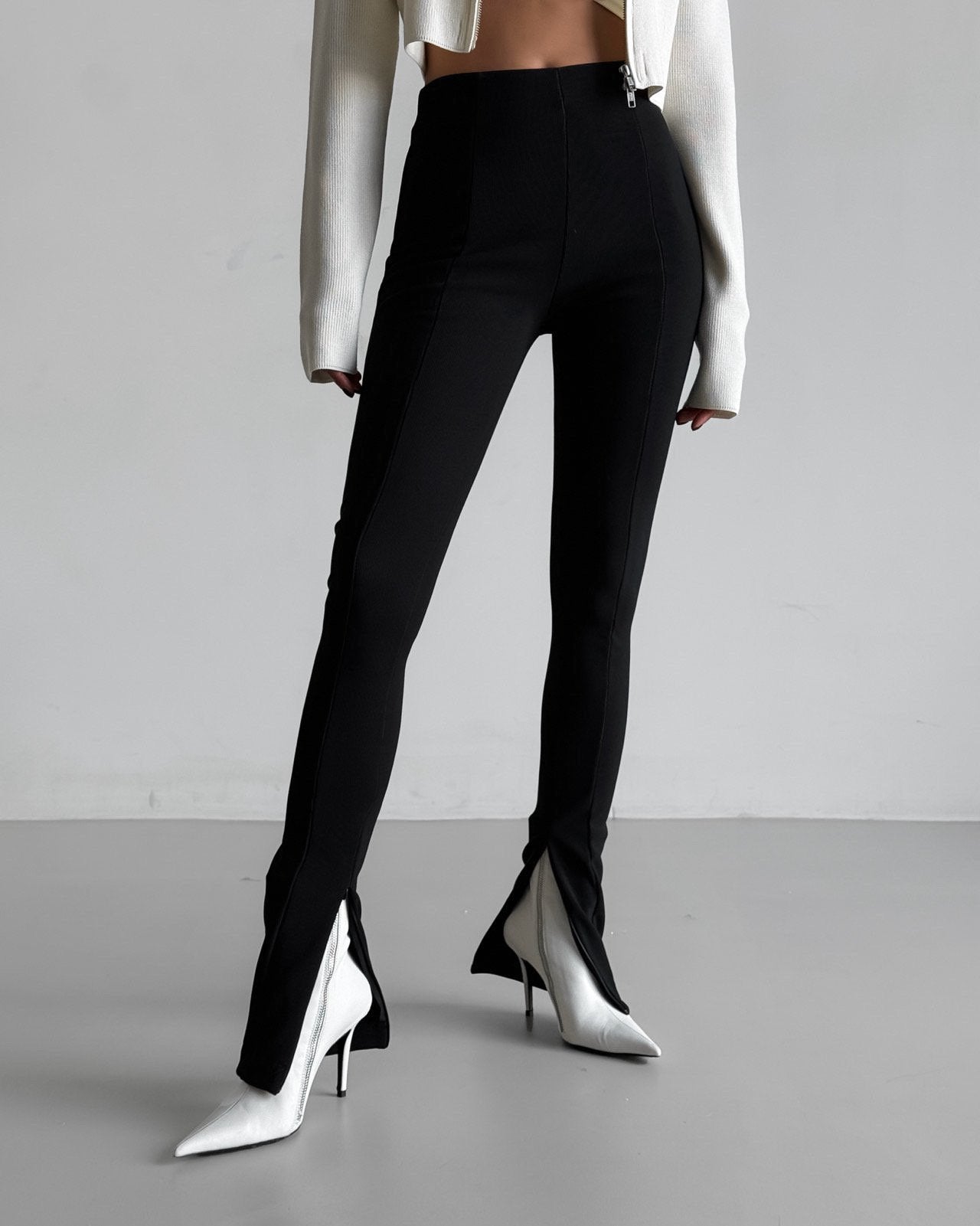 Full-length view of black ribbed leggings with front seam and side slits styled with white top.