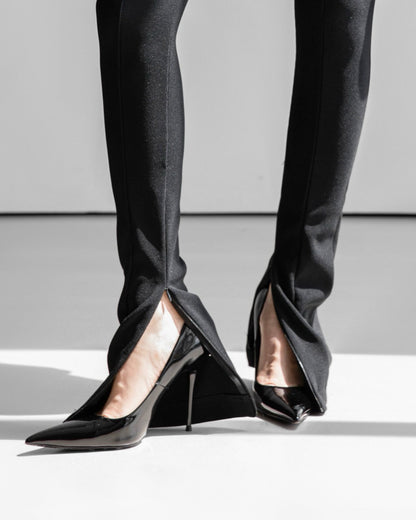 Close-up of side slit hem detail on ribbed black leggings.