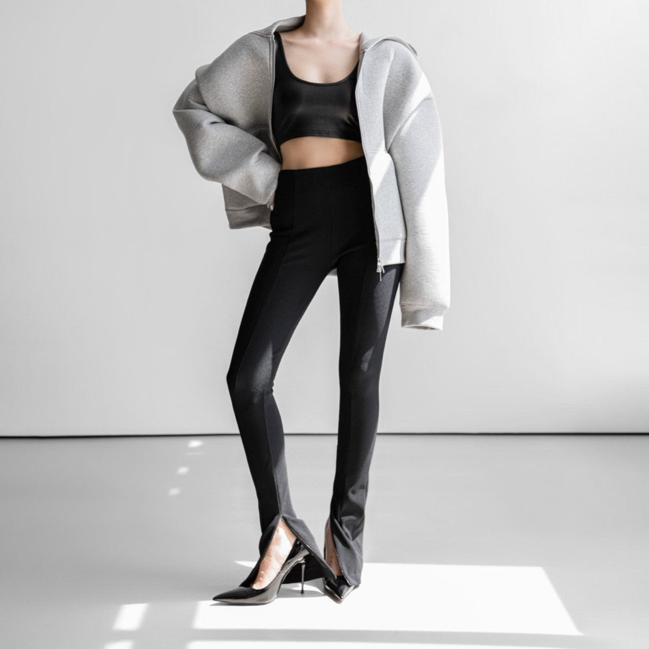 Ribbed black leggings styled with oversized gray hoodie and heels — modern minimal look.