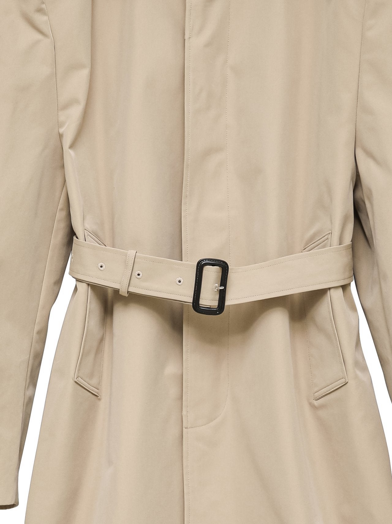 Close-up of matte belt buckle and trench fabric texture.