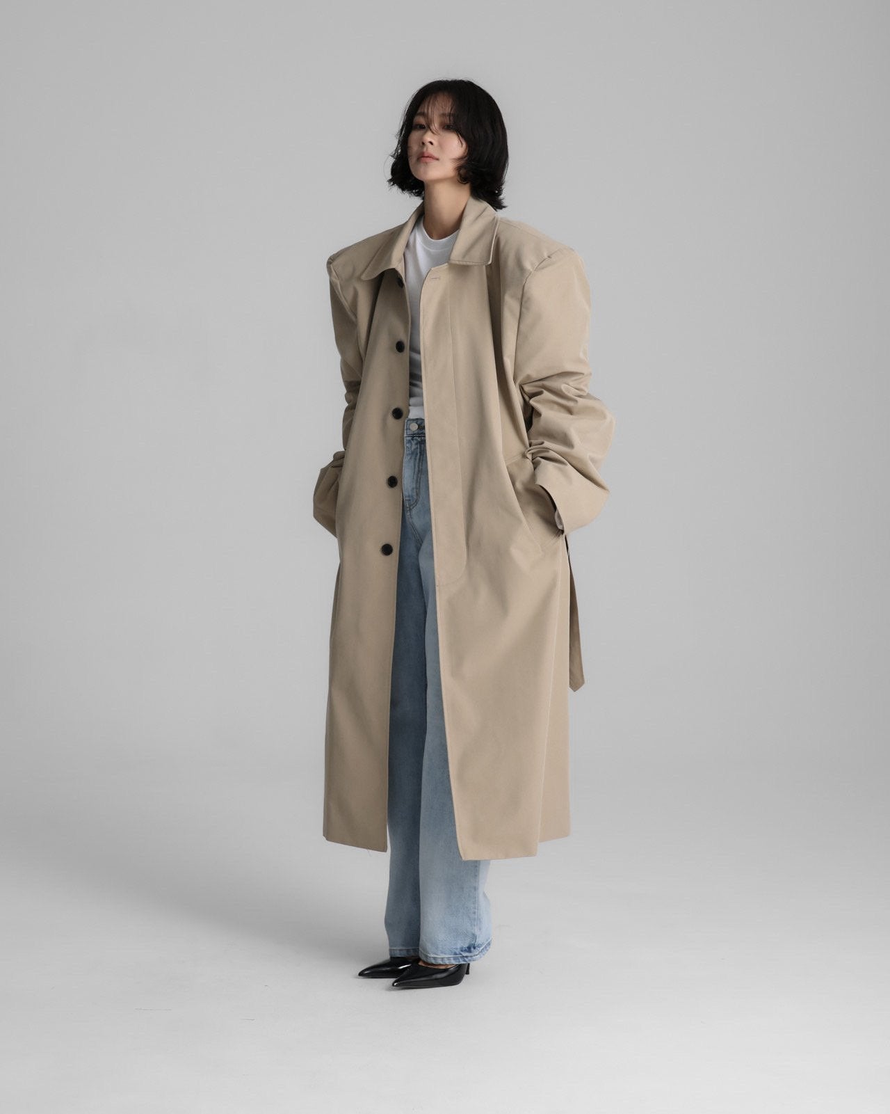 Model wearing the Classic Oversized Structured Trench Coat in beige, showcasing its defined shoulders and elongated silhouette.
