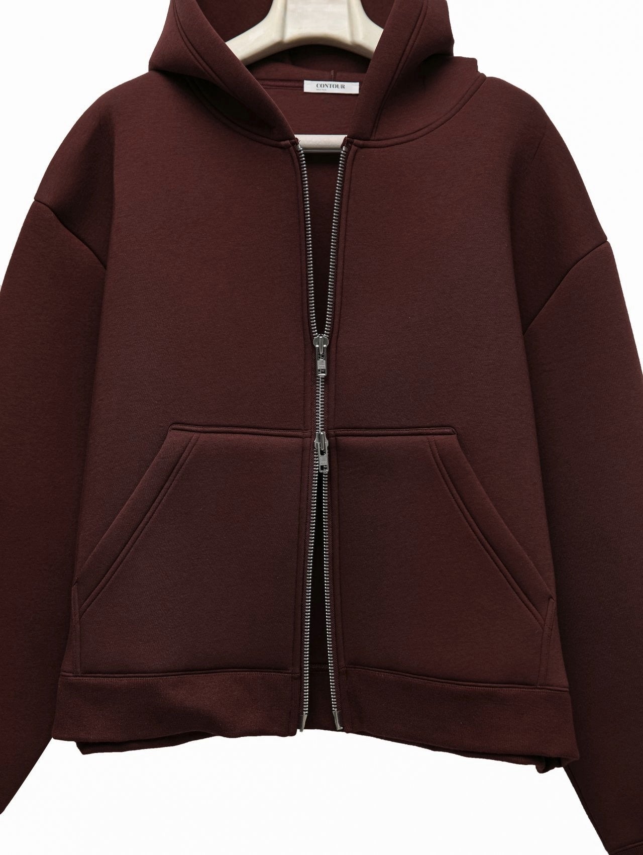 front view of burgundy neoprene hoodie showing sculptural hood and boxy cut