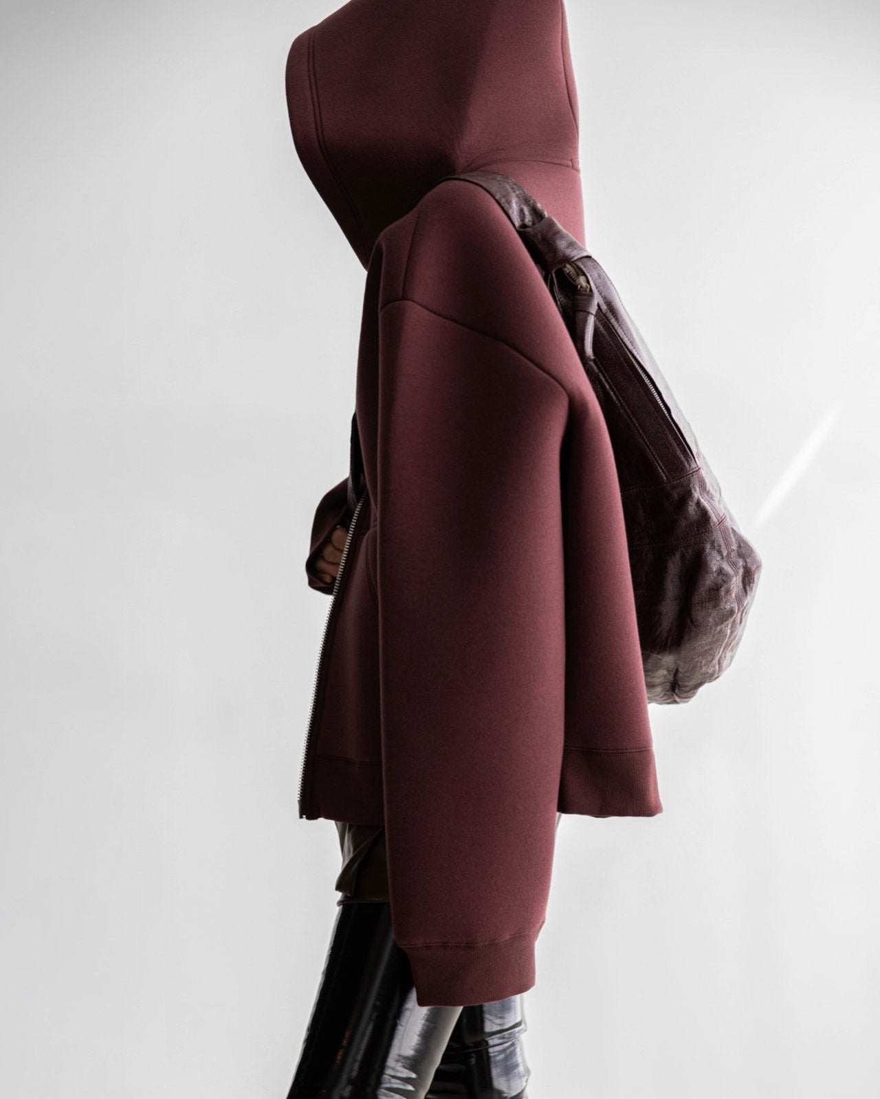 Side profile of structured neoprene hoodie highlighting dropped shoulders and volume