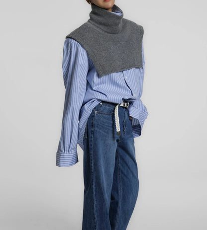 Model wearing the Turtleneck Wool Cape Knit layered over a blue striped shirt and denim, showcasing its sculptural cropped silhouette.