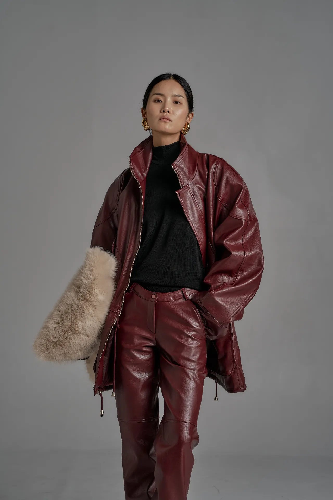 Close-view of oversized wine leather jacket styled with black turtleneck, showing structured shoulders.