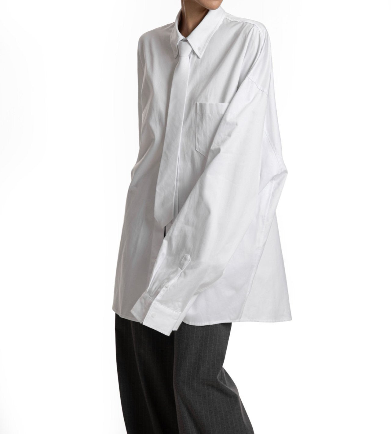 Side view of oversized white button-up shirt — fluid structure and elongated sleeves.