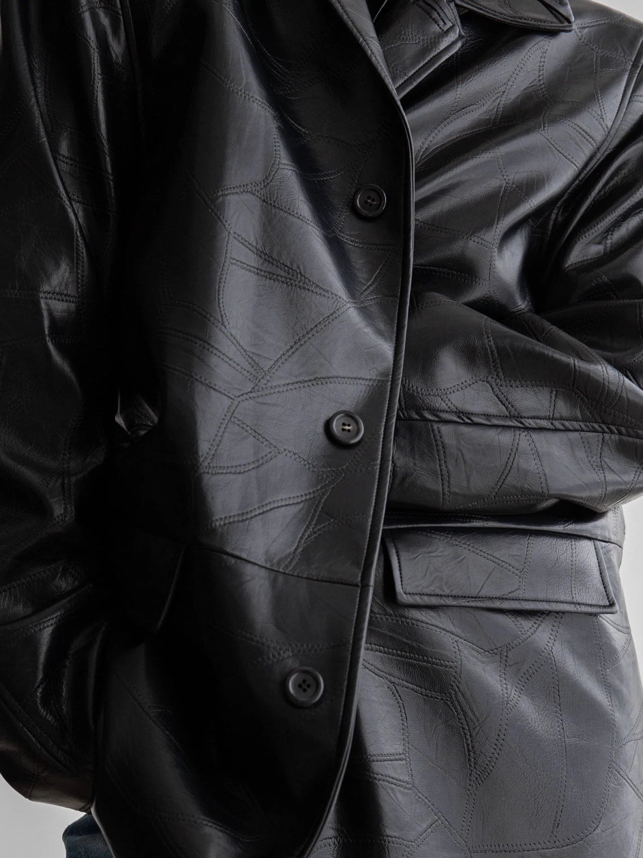 Close-up of black patchwork vegan leather texture and buttons