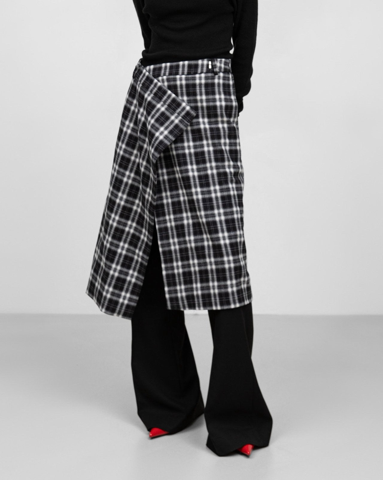 Side view of black-and-white plaid wrap midi skirt showing wrap detail.