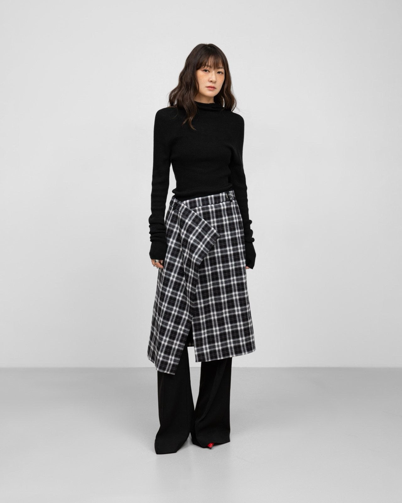 Model wearing black-and-white plaid wrap midi skirt styled with black knit top.