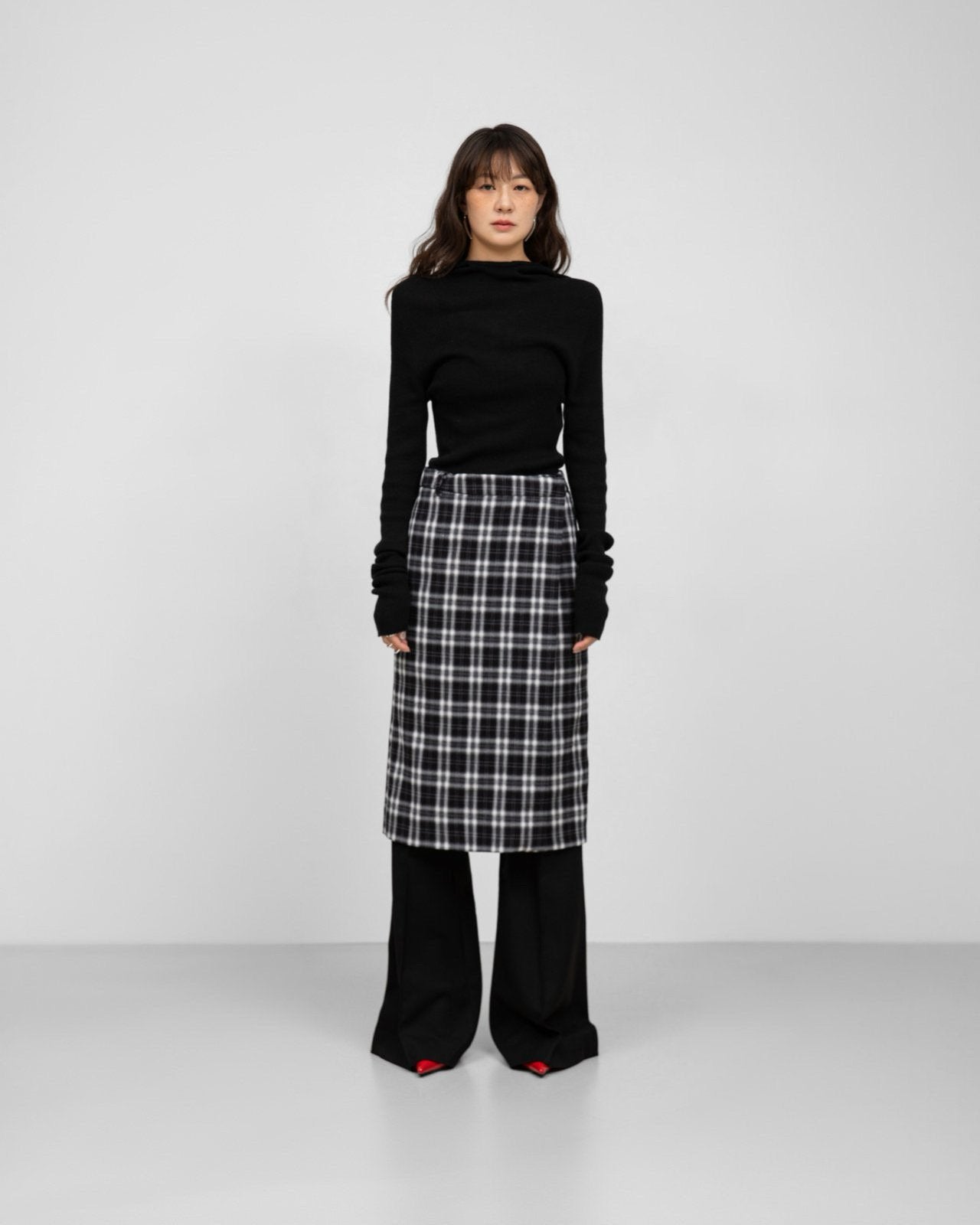 Model wearing black-and-white plaid wrap midi skirt styled with black knit top.