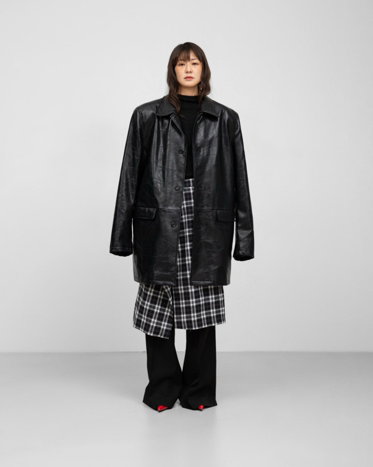 Editorial full-body look with plaid wrap midi skirt and black knit top. and leather patchwork structured half coat