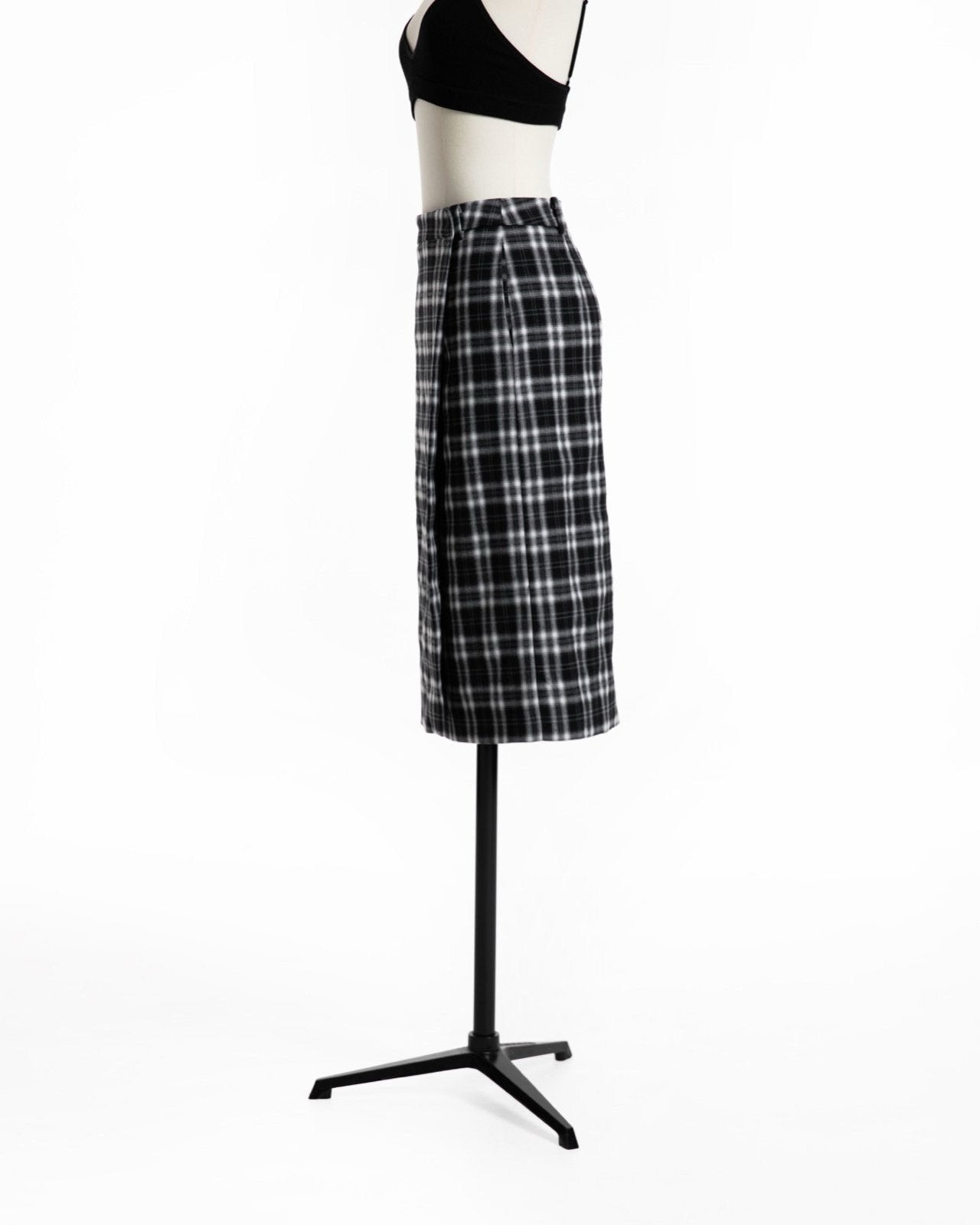 Side view of black-and-white plaid wrap midi skirt showing wrap detail.